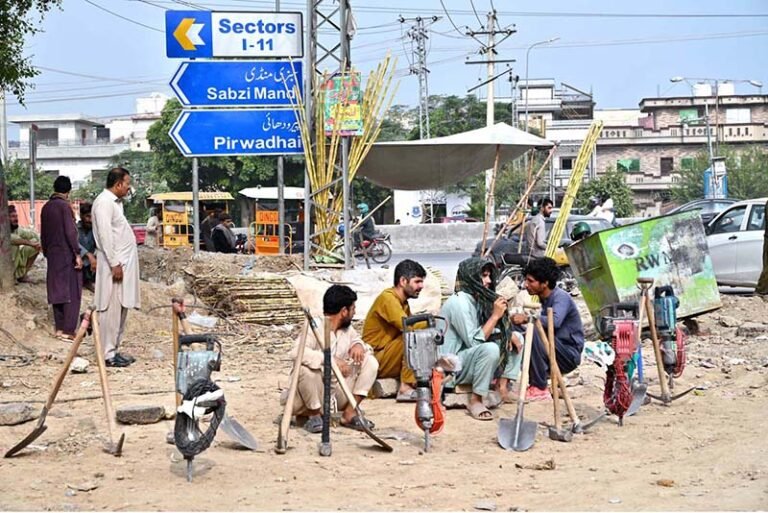 Labourers are sitting with their tools along IJP Road, waiting to be hired.