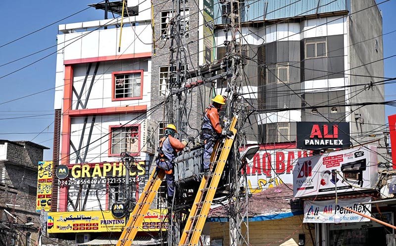 IESCO workers climb electricity poles to repair a fault and restore power at Banni Chowk following a power breakdown in twin cities.