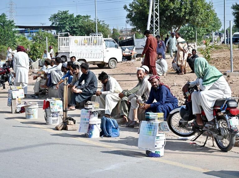 – Labourers sit along the roadside with their tools, waiting to be hired for daily work at the PWD Interchange.