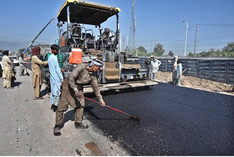 Labourers carry out road construction work at Kashmir Chowk using heavy machinery as the development project progresses in federal capital.