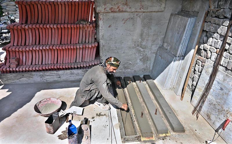 A worker prepares tuff tiles and other cemented items at his workplace in Pindora.