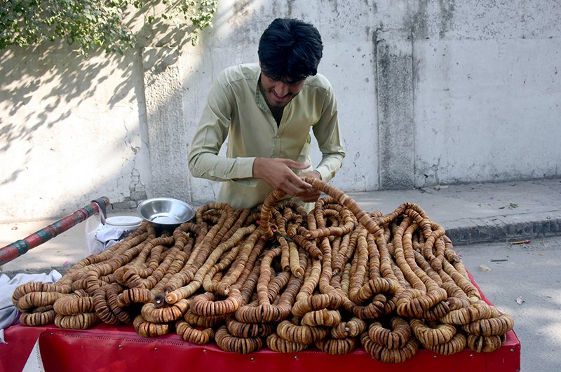 A young vendor arranges to sell dried figs on his handcart by the roadside in provincial capital.