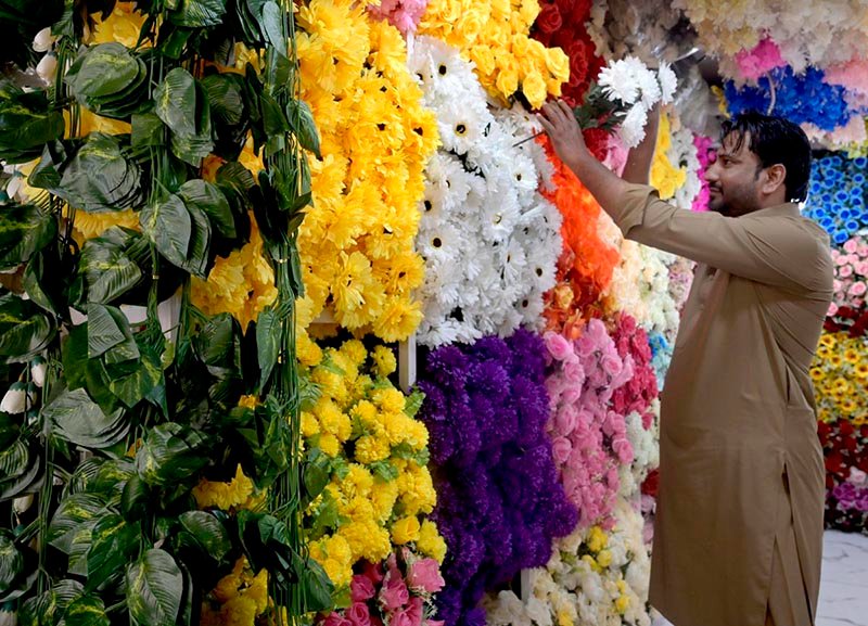 A vendor arranges a wide variety of artificial flowers at his shop in Banni Chowk.