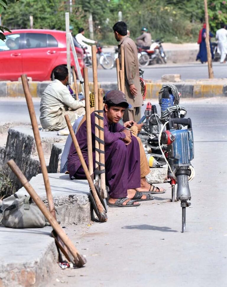 Labourers are sitting with their tools at Trameri Chowk, waiting to be hired.