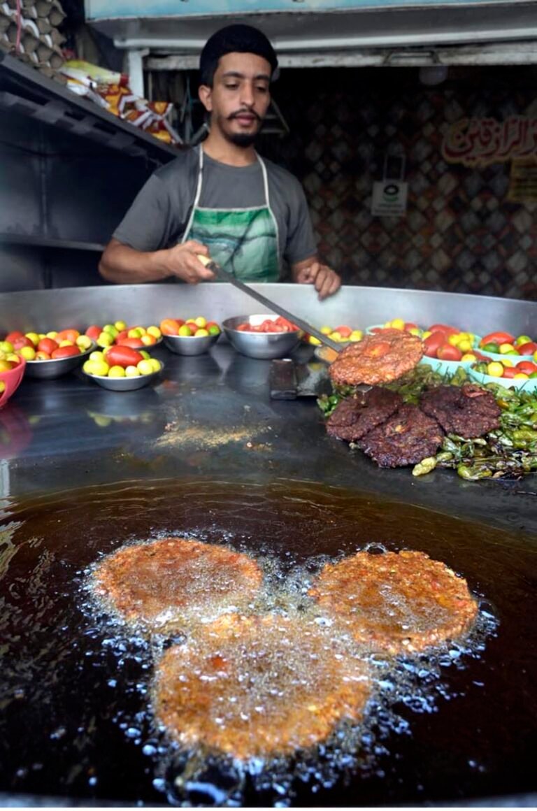 A vendor lifts a freshly fried chapli kebab from sizzling oil to attract customers at his shop in Banni Chowk.