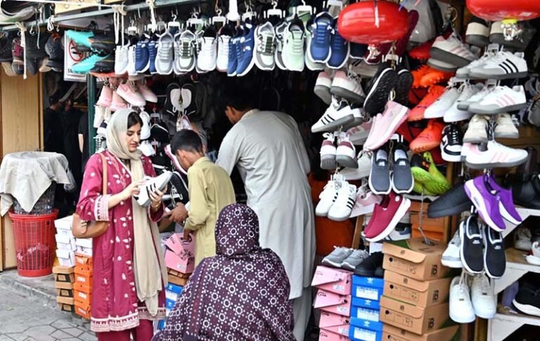 A woman is selecting and purchasing shoes from a stall in Sunday Bazaar at Peshawar Mor in the Federal Capital