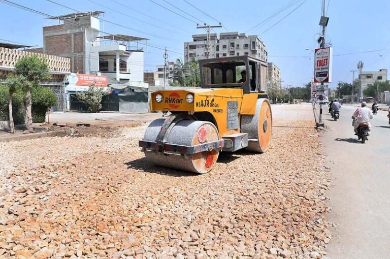 A labourer is busy levelling a new road with the help of a road roller during road construction work at Latifabad Road.