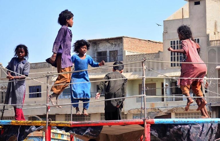Young girls enjoy a playful moment on a jumping jack on a trampoline in the Old Sabzi Mandi area.