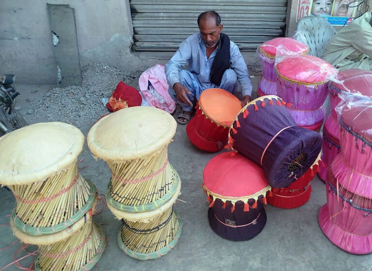 A labourer sits in the shade while crafting bamboo sticks stool for sale to earn his livelihood near Shahdara Road.