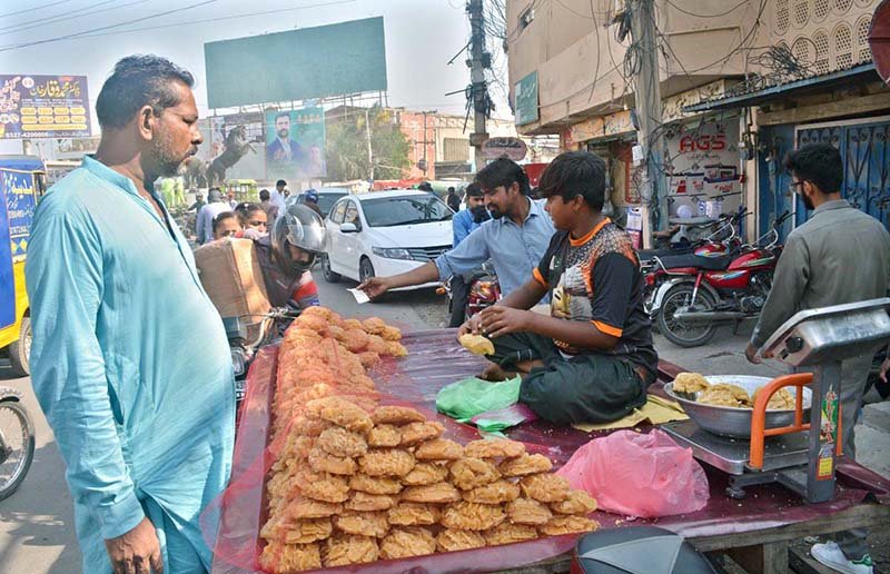 A vendor sells jaggery (gur) to a customer at Khayyam Chowk.