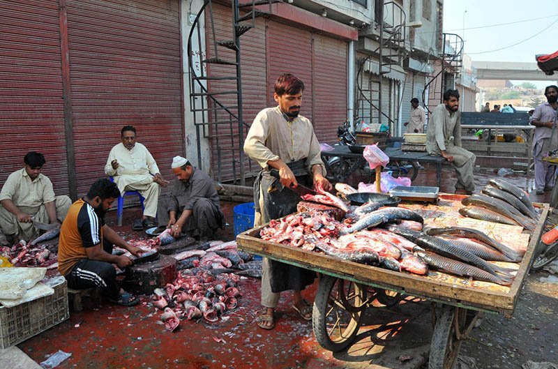 Workers clean fish for customers at a local fish market in the city