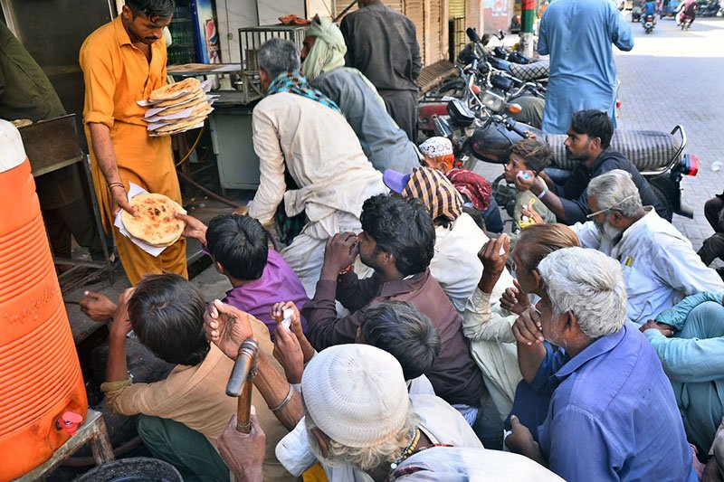 People gather outside a restaurant on Lajpat Road to receive free food distributed by volunteers.
