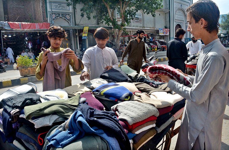 Customers searching for purchase used (second-hand) winter wears at reasonable price at a weekly Friday bazaar.