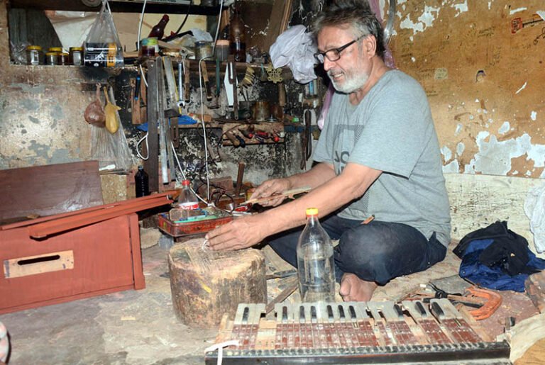 An artisan repairs a harmonium at his workplace