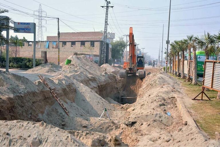 Labourers use heavy machinery to dig trenches to lay a sewerage pipeline along LMO Road near Rajapur as part of ongoing development work
