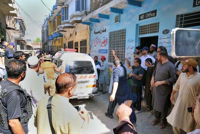 An ambulance shifting injured student and the bodies of several victims to hospital following a school roof collapse in Dir Colony.