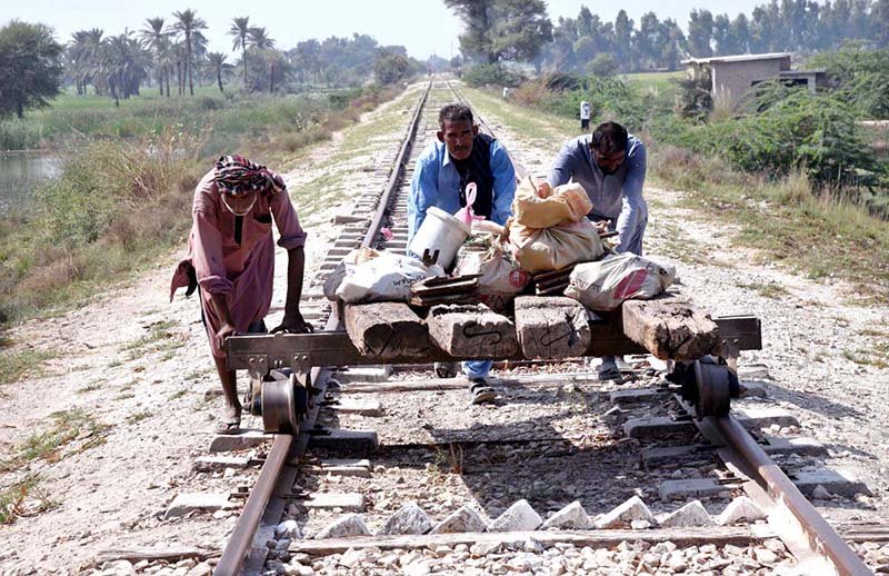 Railway workers manually push a rail trolley loaded with equipment during track maintenance work along Dodai Bypass Road.