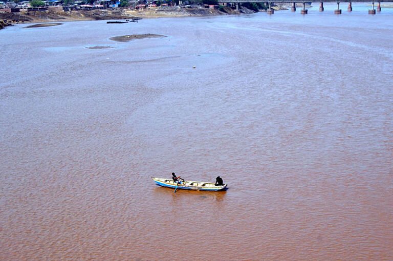 Boatmen row their boats along the Ravi River, creating a scenic view.