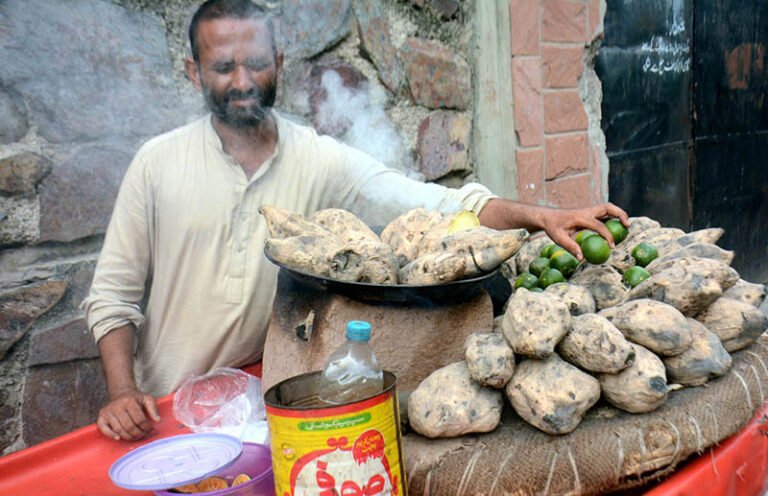 A vendor roasts sweet potatoes on a griddle for sale near the Iron Market in provincial capital.