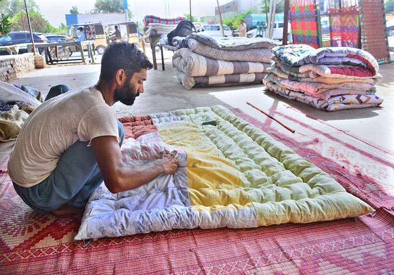 A worker stitches a quilt by hand at his workplace as demand rises ahead of the approaching winter in the city.