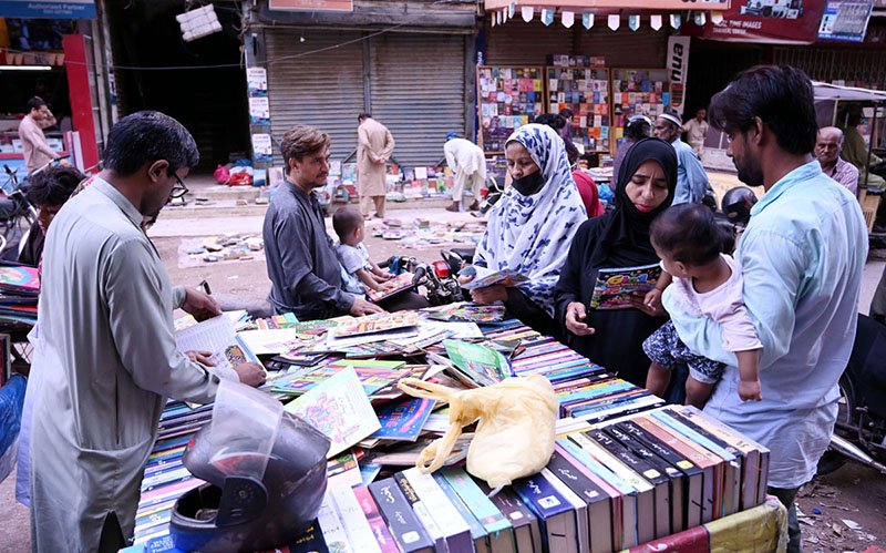 Women browse and purchase books from a street vendor’s cart in the Saddar area