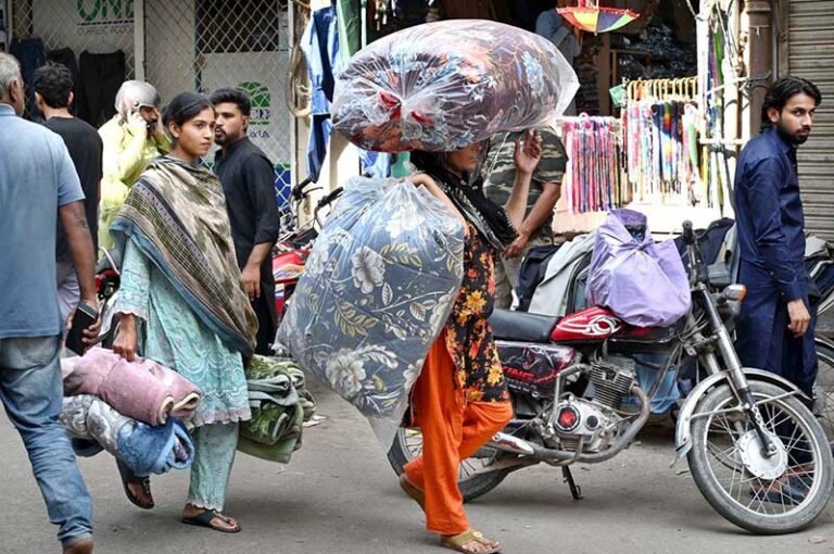 A woman carries cotton-filled quilts (razais) as the weather begins to turn cooler in the city