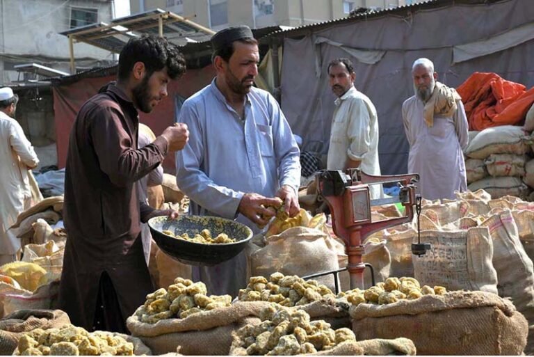 A shopkeeper weighs sacks of traditional jaggery (gur) a natural sweetener at Gur Mandi.