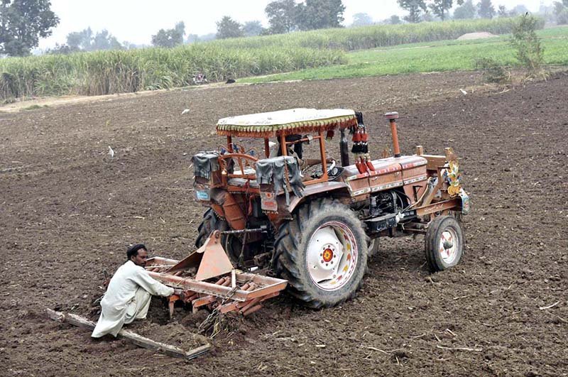 A farmer levels his field with a tractor in preparation for the next crop