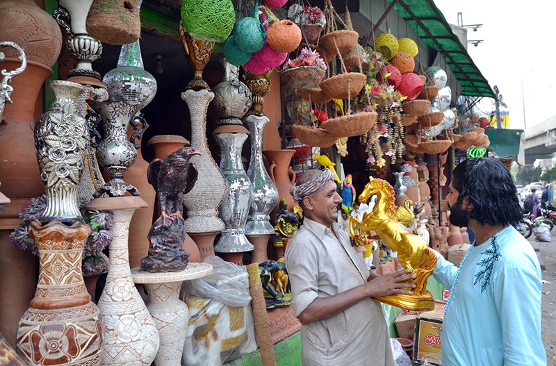 A shopkeeper shows a golden horse statue to a customer at his decorative items shop near Kalma Chowk