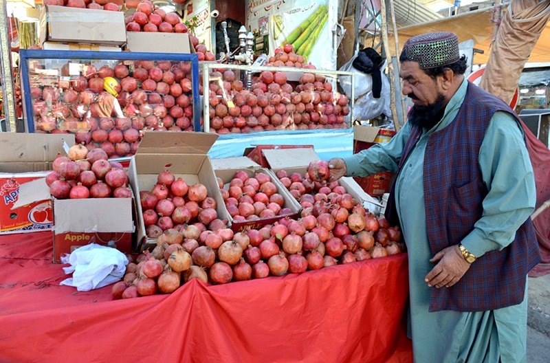 A vendor decorates pomegranates to attract customers at Meezan Chowk