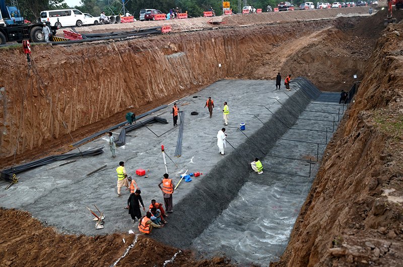 Workers are engaged in construction work on the underway Kashmir Chowk Underpass (Dhokri Chowk) project along Murree Road in the Federal Capital.