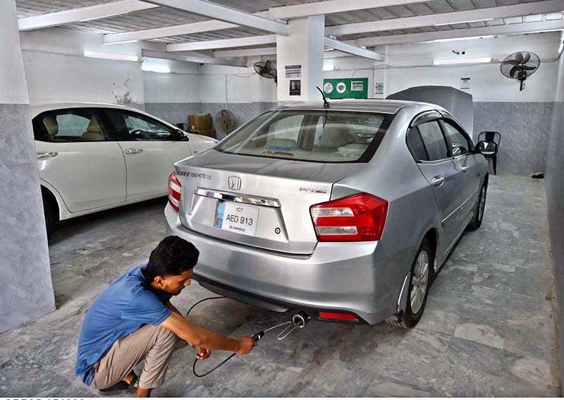 Worker busy in vehicle emissions test at private vehicle inspection and certification center.