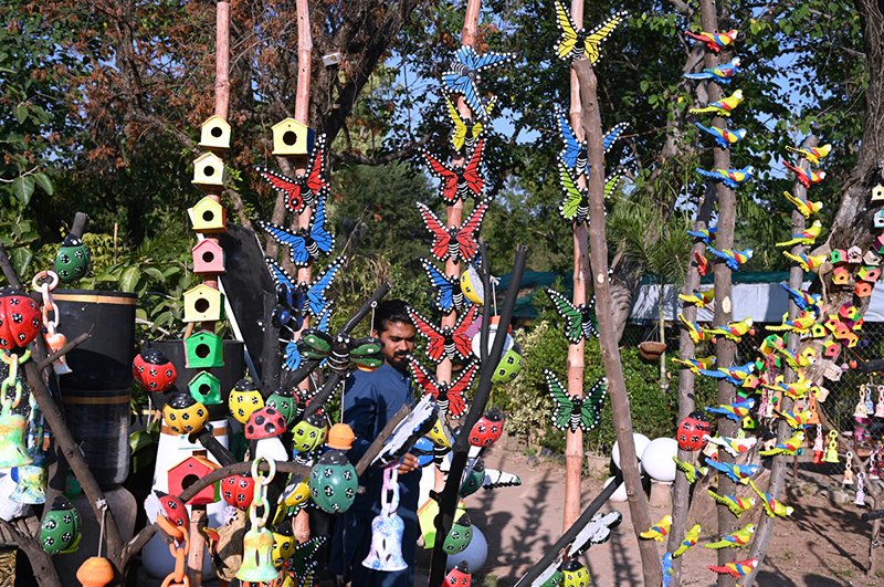 A vendor displays clay made pots and crafted artificial bird nests for garden décor to attract customers at park road
