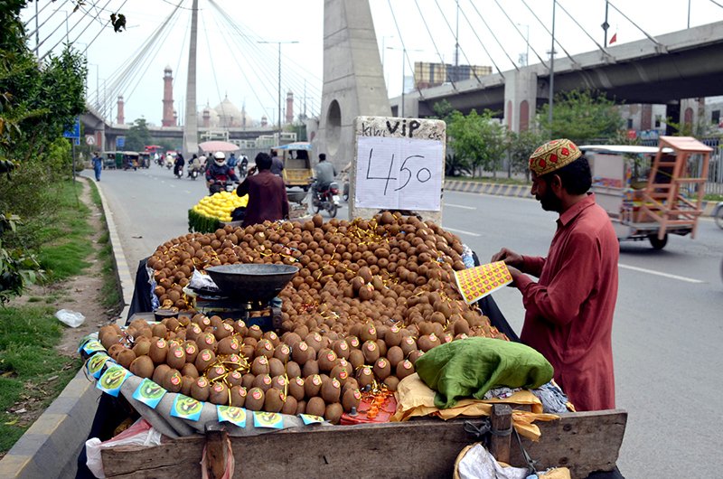 A vendor is putting stickers on kiwis at his roadside setup on Ravi Road.