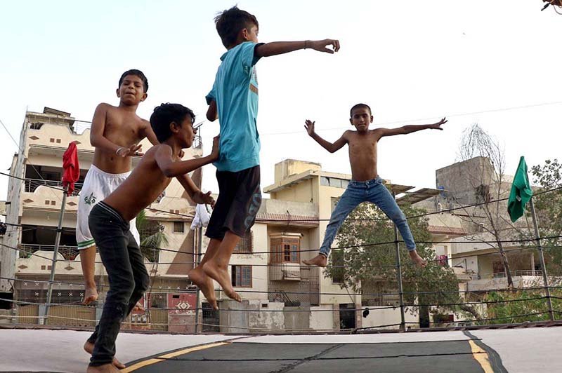 Children enjoying and jumping on trampoline along the roadside during hot weather in the city