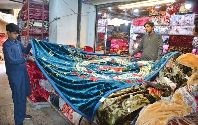 A shopkeeper displays blankets for sale at his shop ahead of the winter season.