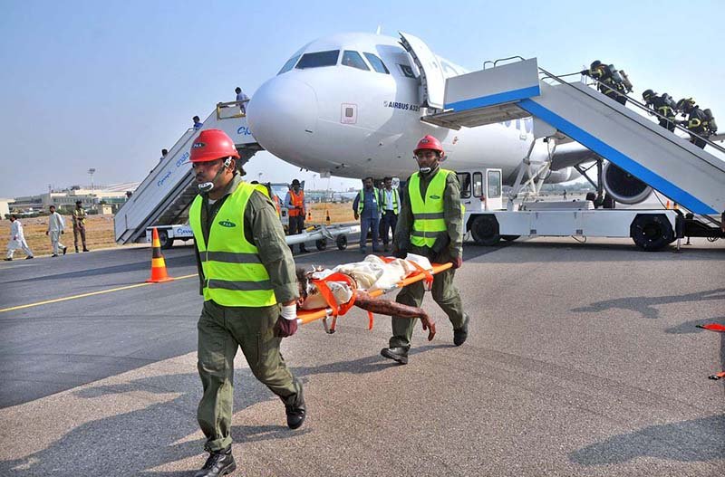 Fire and rescue personnel carry a simulated burn victim on a stretcher away from an Airbus A321 aircraft during a Full-Scale Emergency Exercise conducted by the Pakistan Airports Authority (PAA) at Multan International Airport to evaluate staff operational readiness and emergency evacuation procedures
