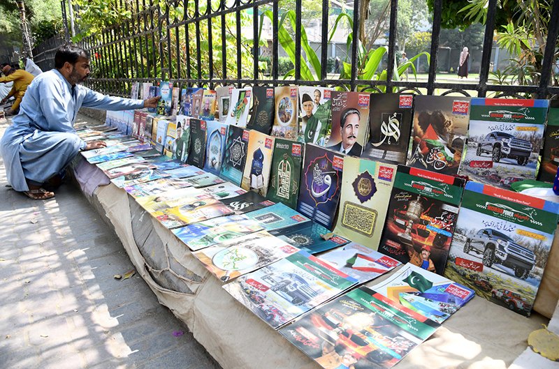 A vendor arranging and displaying different books to attract the customers at Jinnah Bagh