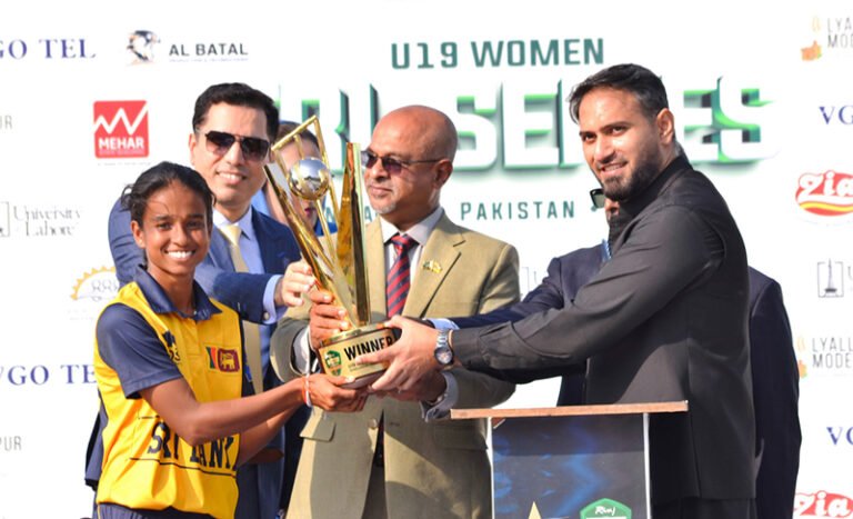 Divisional Commissioner Dr. Imran Hamid Sheikh and Sri Lankan High Commissioner Admiral Fred Seneviratne present the trophy to the captain of the victorious Sri Lanka Under-19 Women’s team after the T20 tri-series final at Iqbal Stadium.