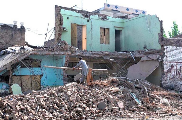 A house is being demolished during an anti-encroachment operation carried out on the instructions of Deputy Commissioner Afaq Wazir, while family members remove belongings and debris from the demolished structure along Ring Road