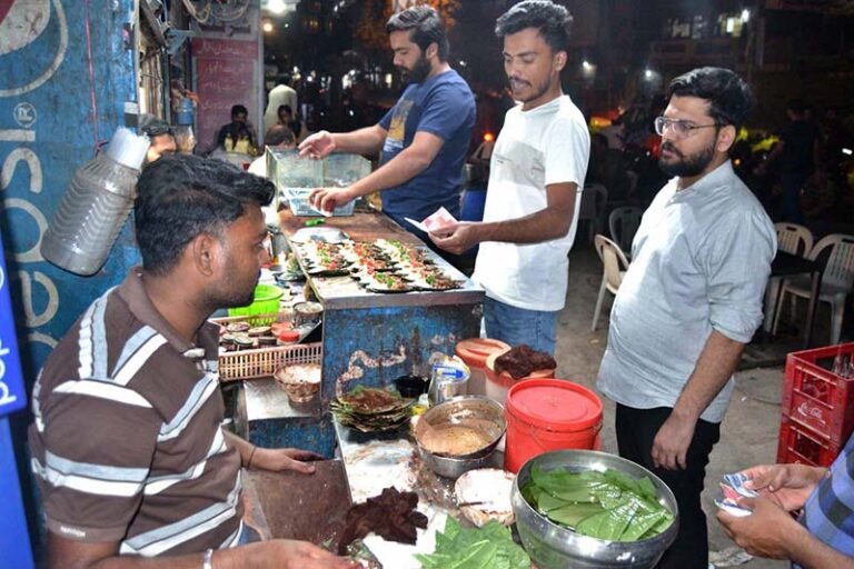 A paan vendor dips betel leaves in water to keep them fresh and clean while preparing paan for customers at Lakshmi Chowk.
