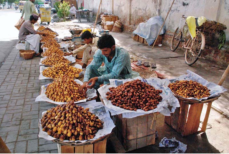 A vendor displays various varieties of dates at a roadside stall to attract passersby and earn a livelihood for his family